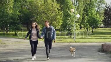 一对年轻的已婚夫妇在公园里跑步，小狗享受自由，与美丽的人一起活动